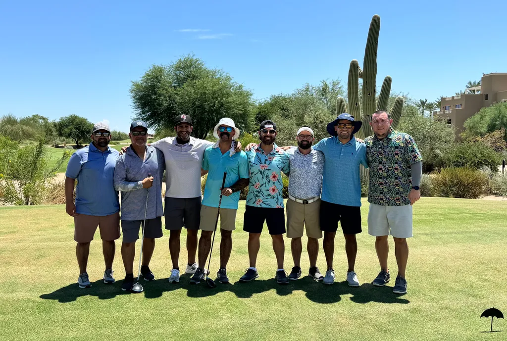 A group posing together on a golf course beneath a blue sky.