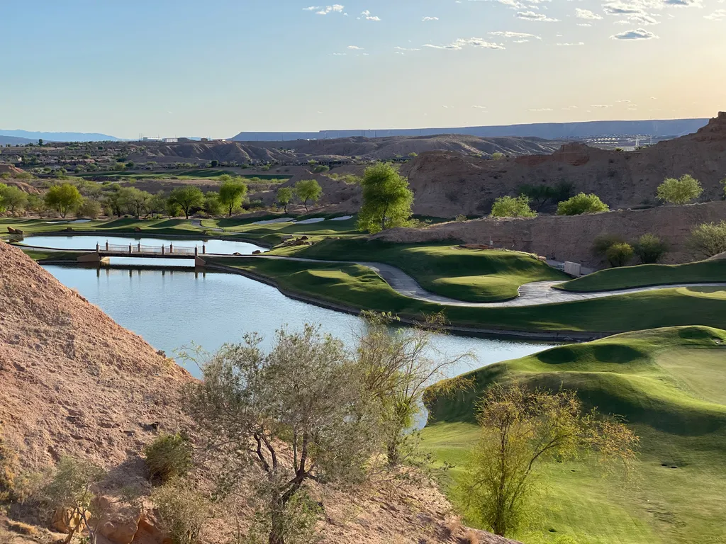 Golf greens, water and a bridge among rocky hills.